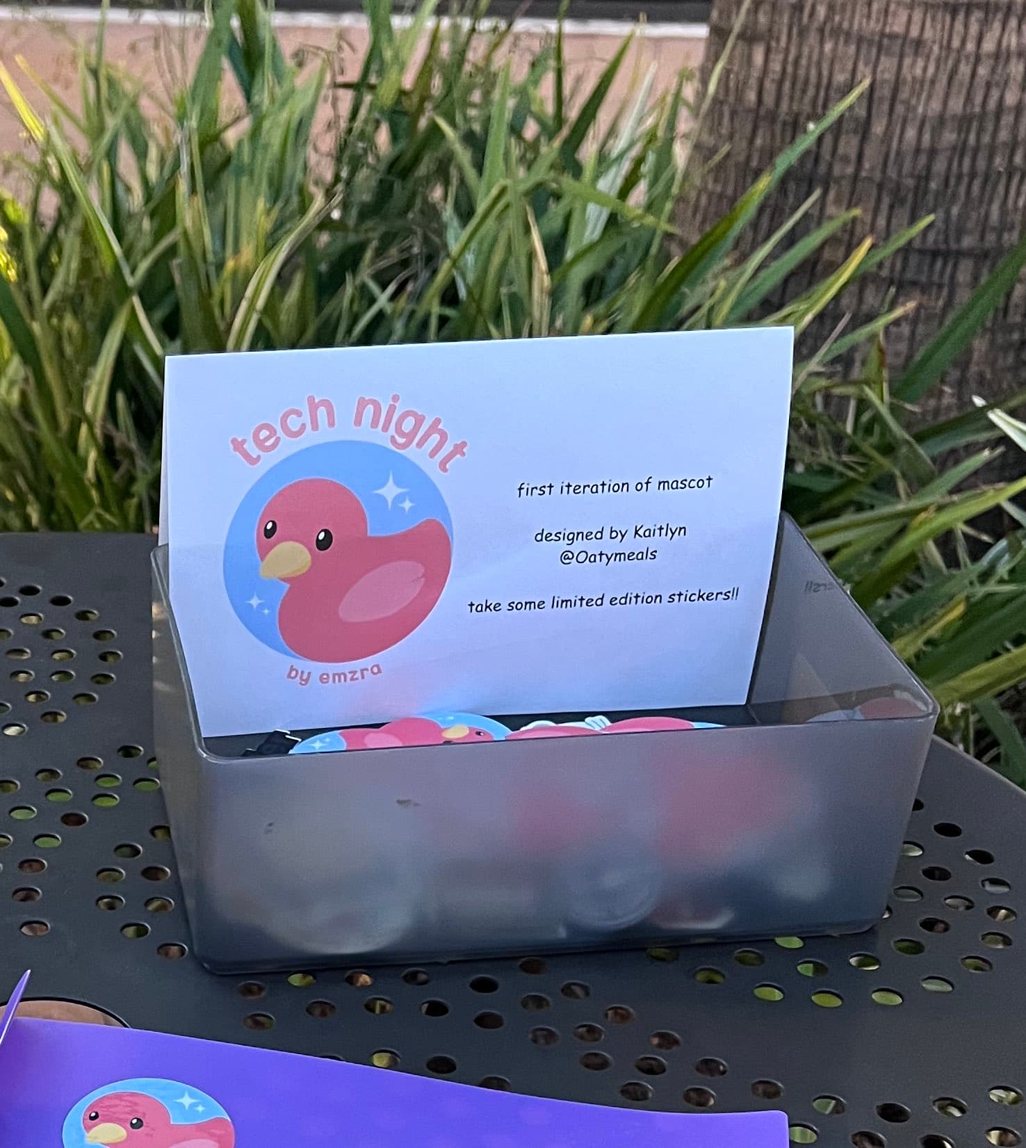 A pink tech night welcome sign beside a tray of name tags
